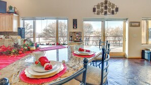 A spacious kitchen with a large island, a dining area with a glass top table, and a view through large windows. - Scenic Great Falls Retreat On Missouri River! (Great Falls)
