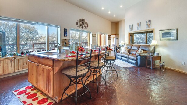 A spacious kitchen with a large island, bar stools, and a dining area with a leather couch. - Scenic Great Falls Retreat On Missouri River! (Great Falls)