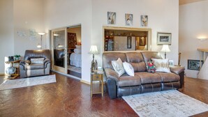 A spacious living room with a leather sofa, a leather armchair, and a large mirror. There are two lamps on side tables and a globe on a small table. - Scenic Great Falls Retreat On Missouri River! (Great Falls)