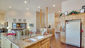 A kitchen with wooden cabinets, granite countertops, a sink, and a refrigerator. - Scenic Great Falls Retreat On Missouri River! (Great Falls)