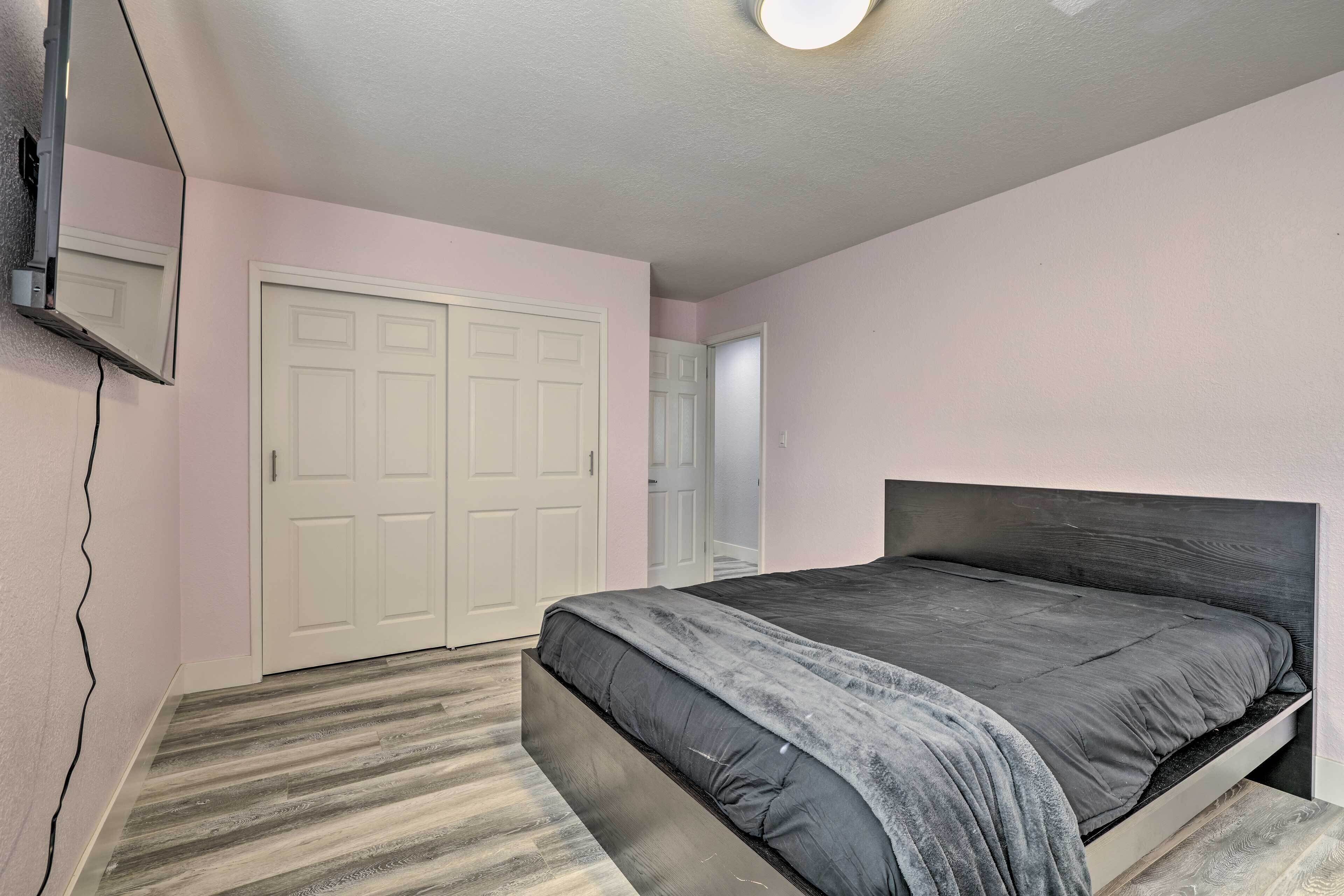 Un dormitorio con cama, armario y espejo en la pared.
