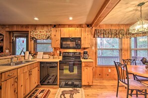 A wooden kitchen with a microwave, stove, and sink. - Private Gatlinburg Cabin: Pet Friendly w/ Hot Tub! (Gatlinburg)