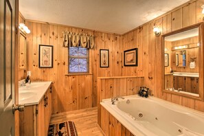 A wooden-paneled bathroom with a large bathtub, two sinks, and framed pictures on the walls. - Private Gatlinburg Cabin: Pet Friendly w/ Hot Tub! (Gatlinburg)