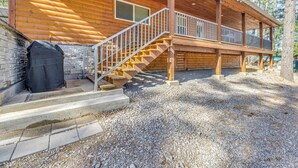 A wooden cabin with a covered porch, stone steps, and a grill outside. - Ruidoso Cabin w/ Patio - Walk to Midtown! (Ruidoso)