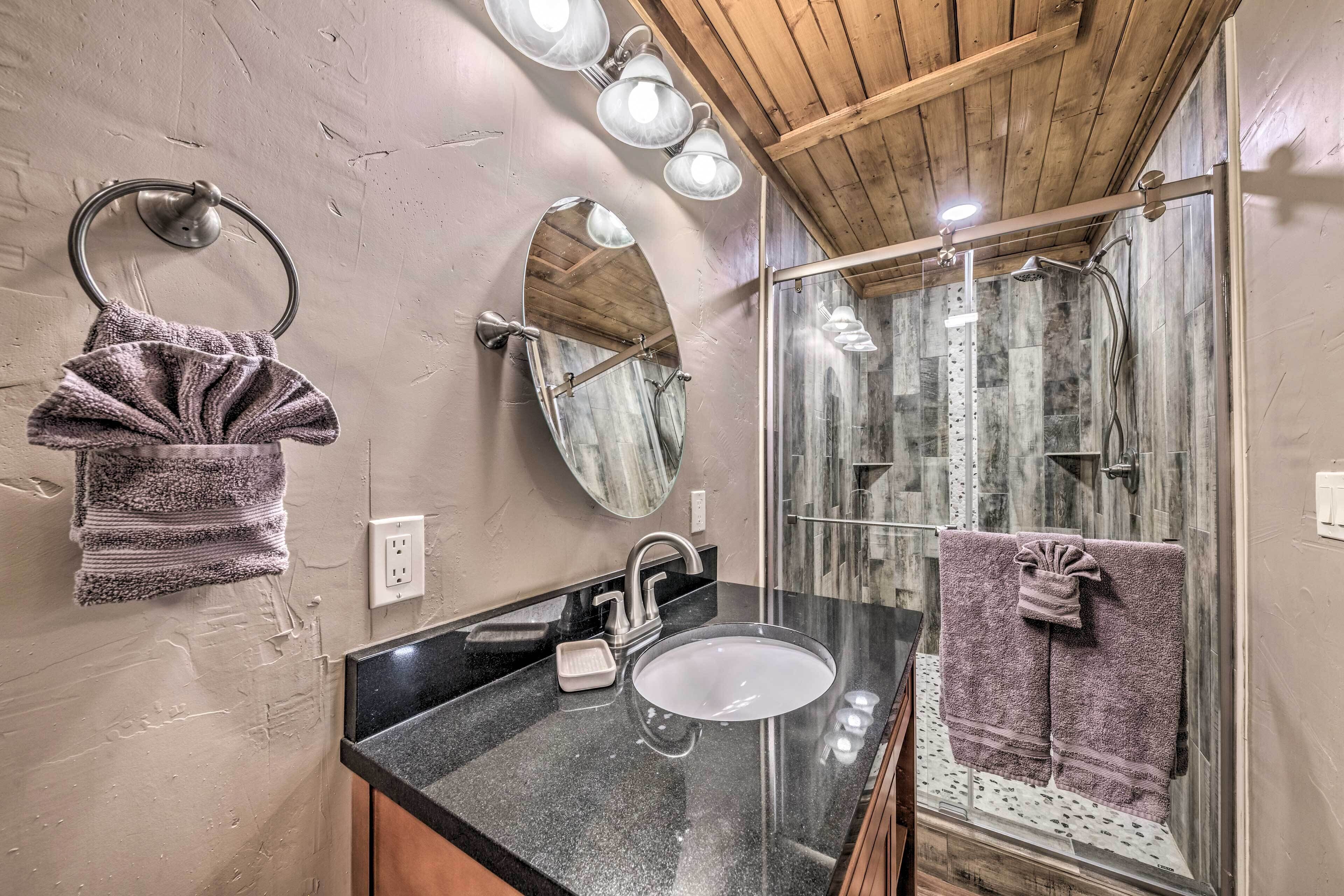 A bathroom with a black countertop sink, a mirror, and a towel rack.