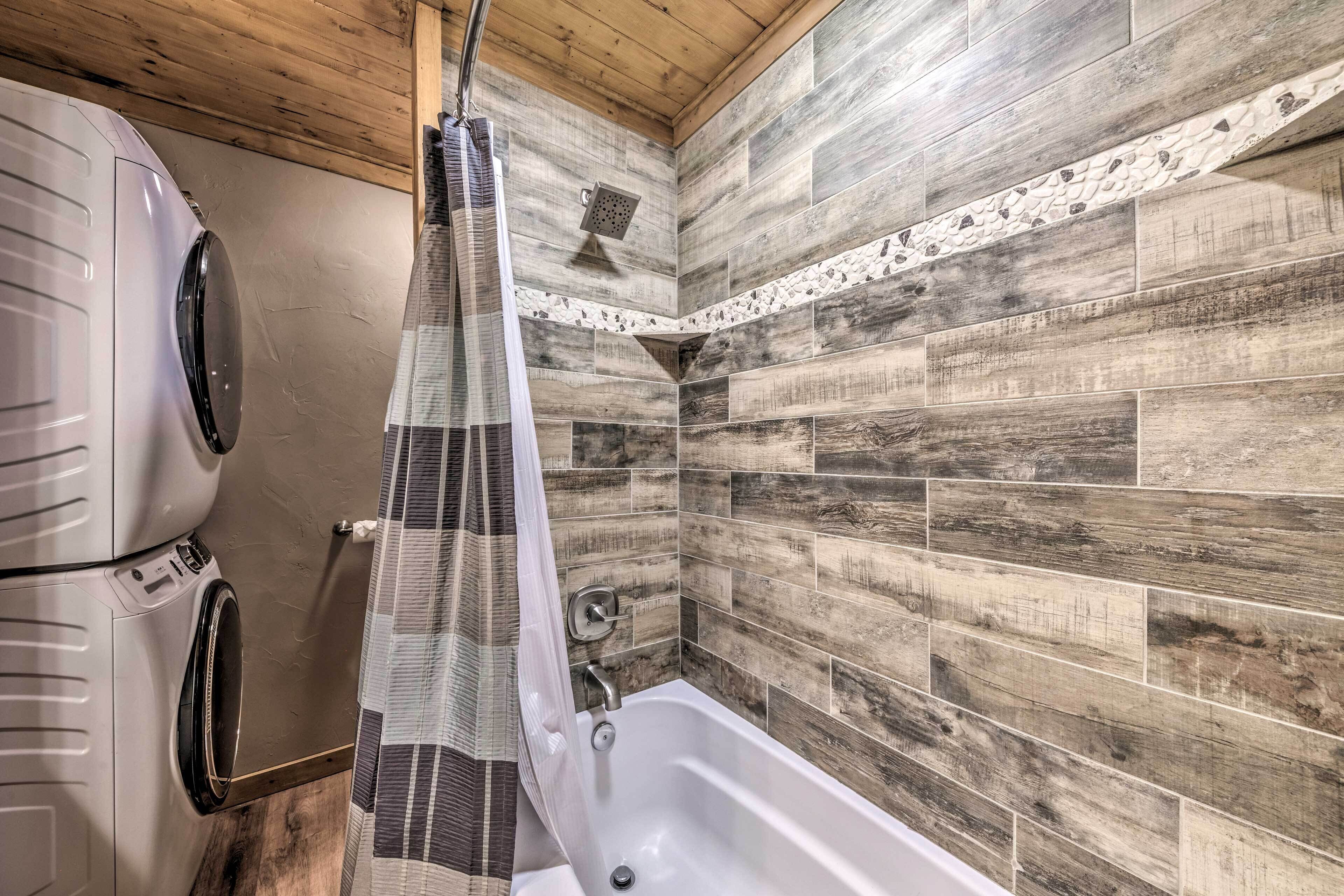 Un baño con techo de madera, una bañera y una lavadora.