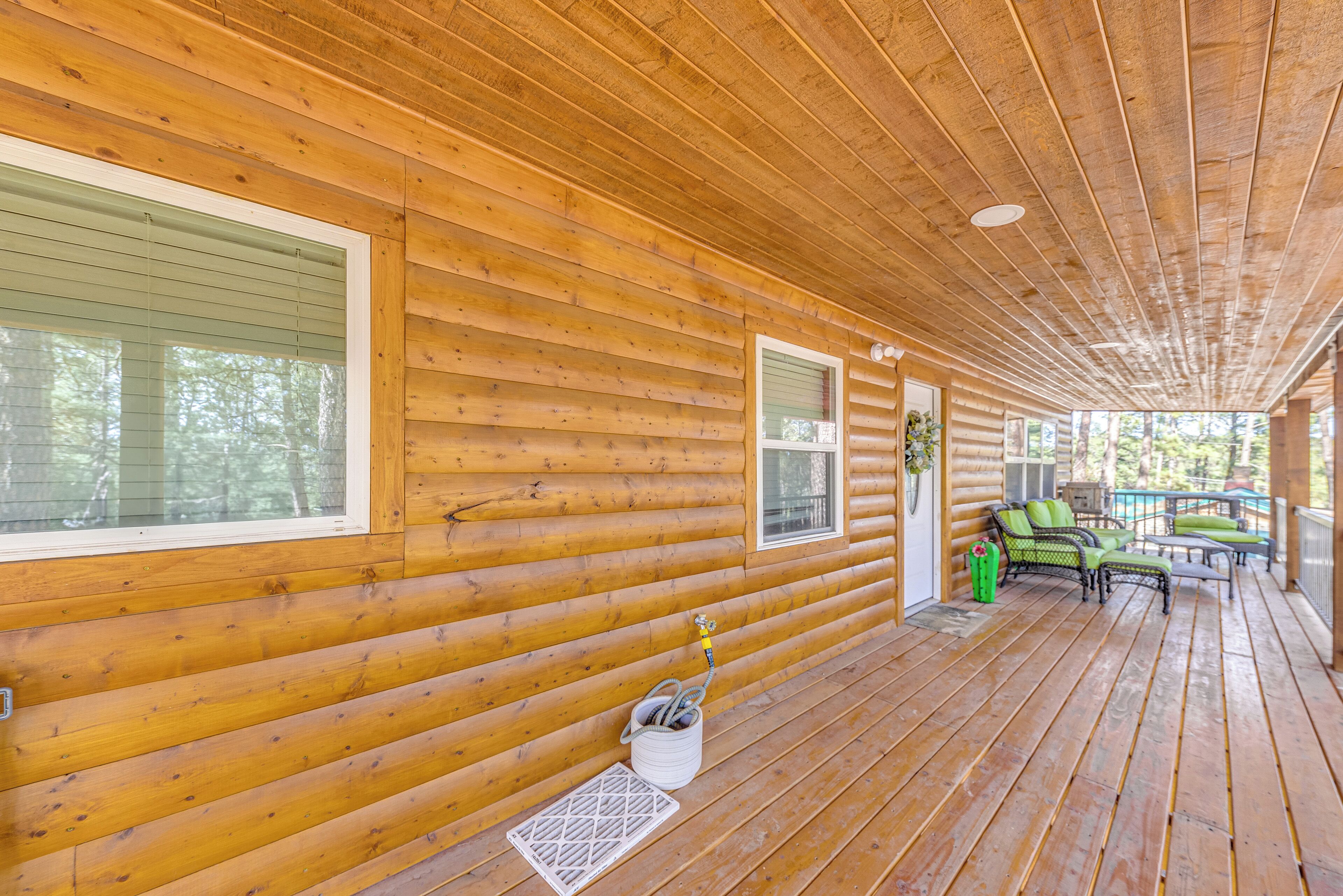 A wooden cabin with a covered porch, large windows, and outdoor seating.