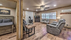 A cozy living room with a fireplace, comfortable seating, and a ceiling fan. - Ruidoso Cabin w/ Patio - Walk to Midtown! (Ruidoso)