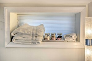 A white storage unit with towels and jars.