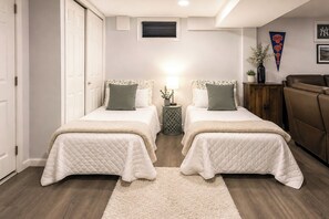 A bedroom with two beds, a nightstand, a lamp, a plant, and a couch. - Saddle Brook Studio With Patio - Near Nyc! (Saddle Brook)