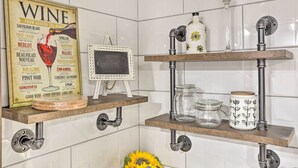 A kitchen with white tiled walls, wooden shelves, and a wine-themed poster. - Saddle Brook Studio With Patio - Near Nyc! (Saddle Brook)