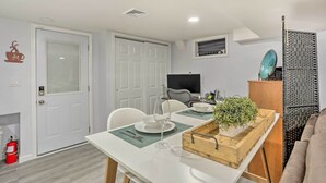 A modern living room with a dining area, white walls, and a flat-screen TV mounted on the wall. - Saddle Brook Studio With Patio - Near Nyc! (Saddle Brook)