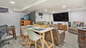 A modern living room with a dining area, a sofa, a TV, and a wooden cabinet. - Saddle Brook Studio With Patio - Near Nyc! (Saddle Brook)