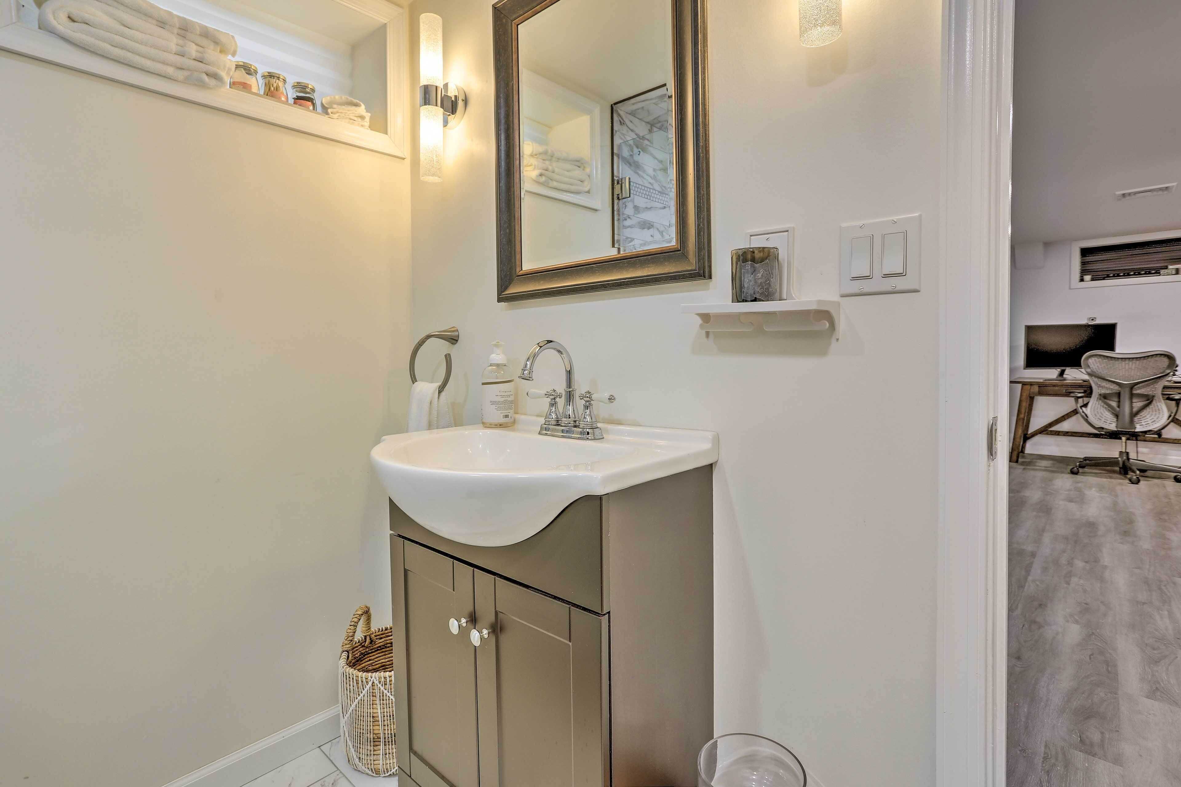 A bathroom with a white sink, a mirror, and a shower area.