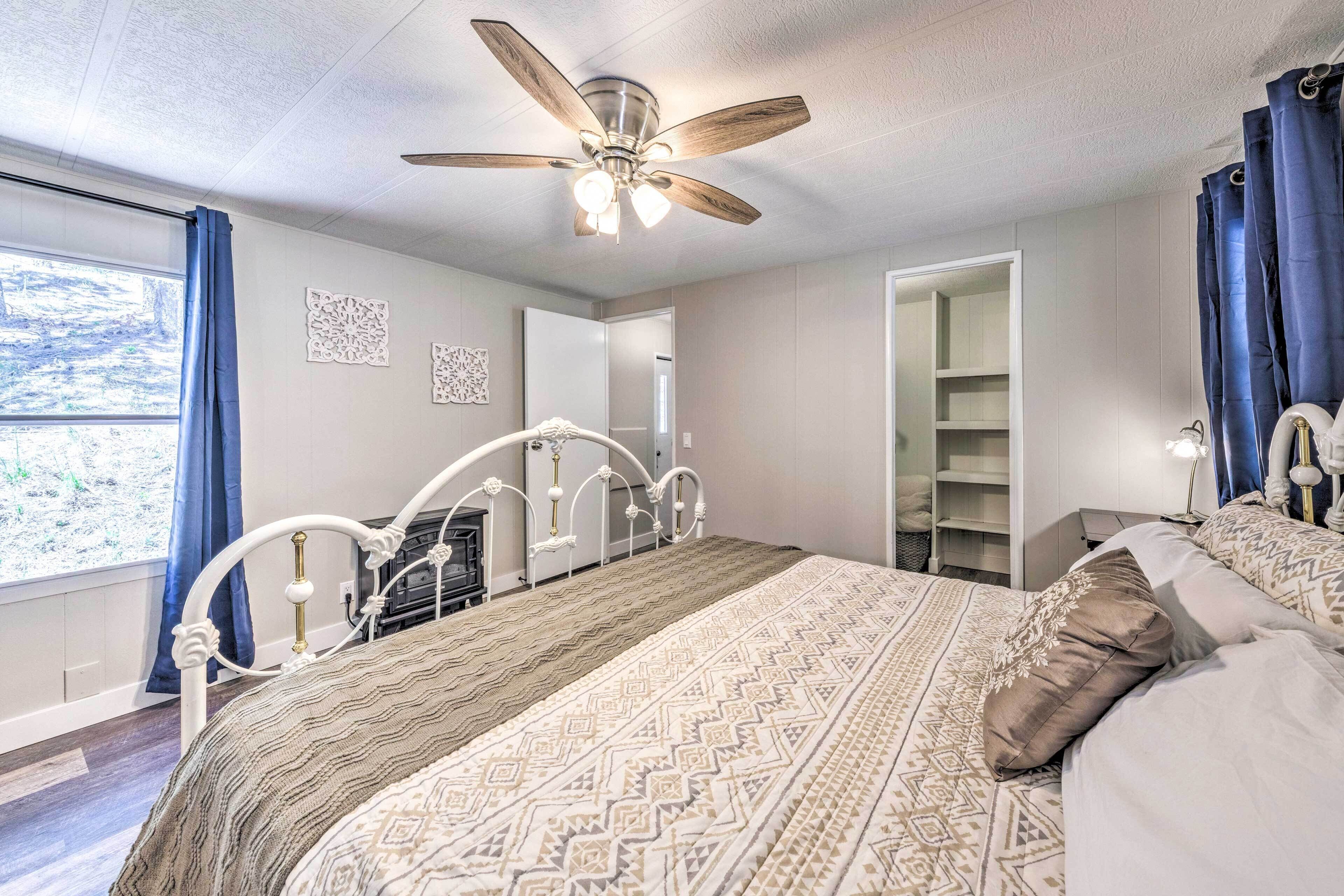 A bedroom with a bed, a ceiling fan, a wardrobe, and a window with curtains.