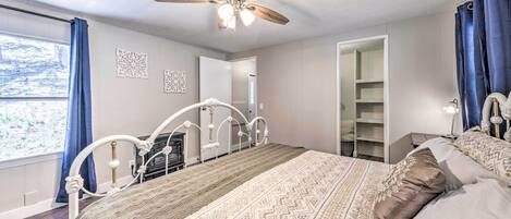 A bedroom with a bed, a ceiling fan, a wardrobe, and a window with curtains.
