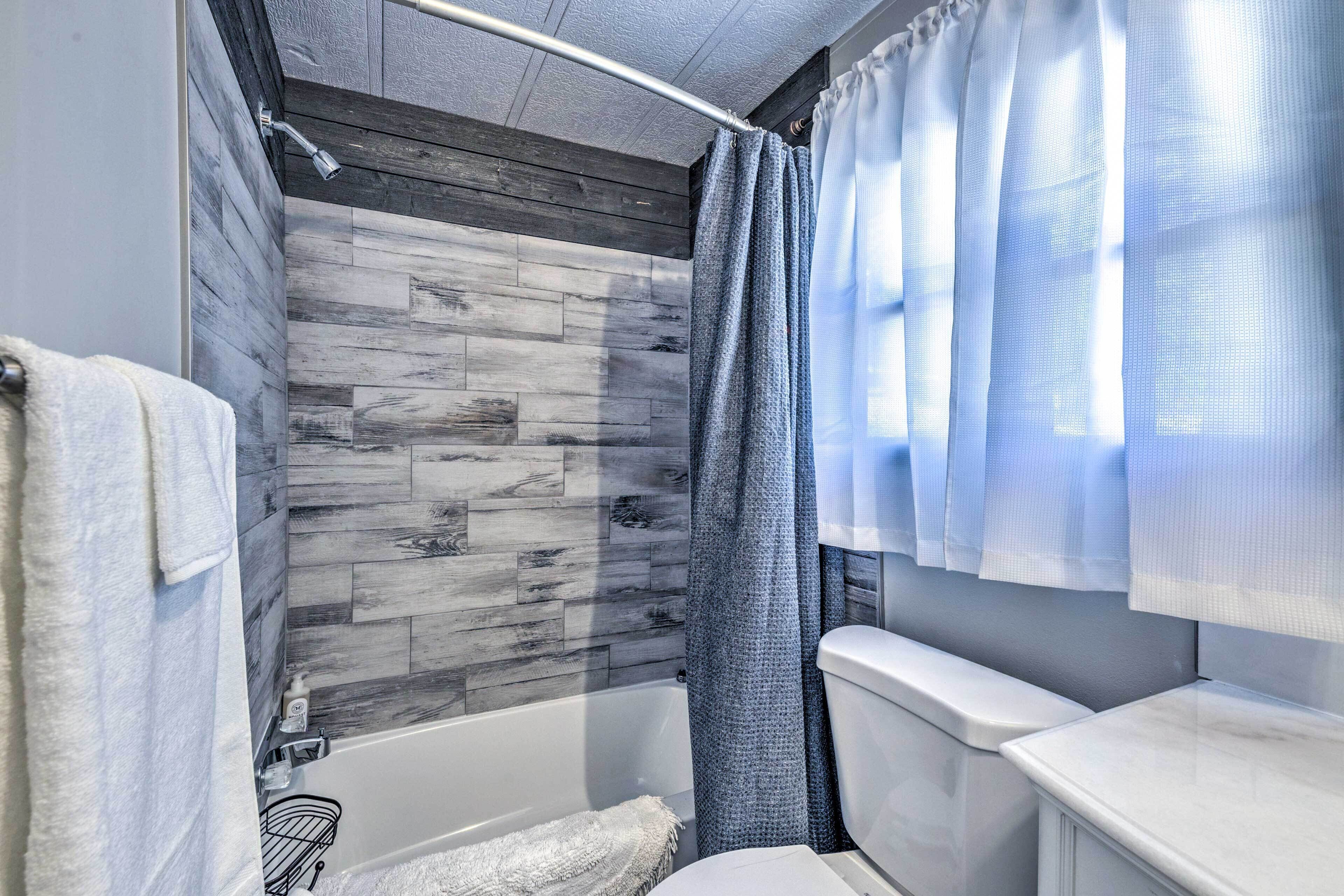 A bathroom with a wooden wall design, a bathtub, a toilet, and a shower curtain.