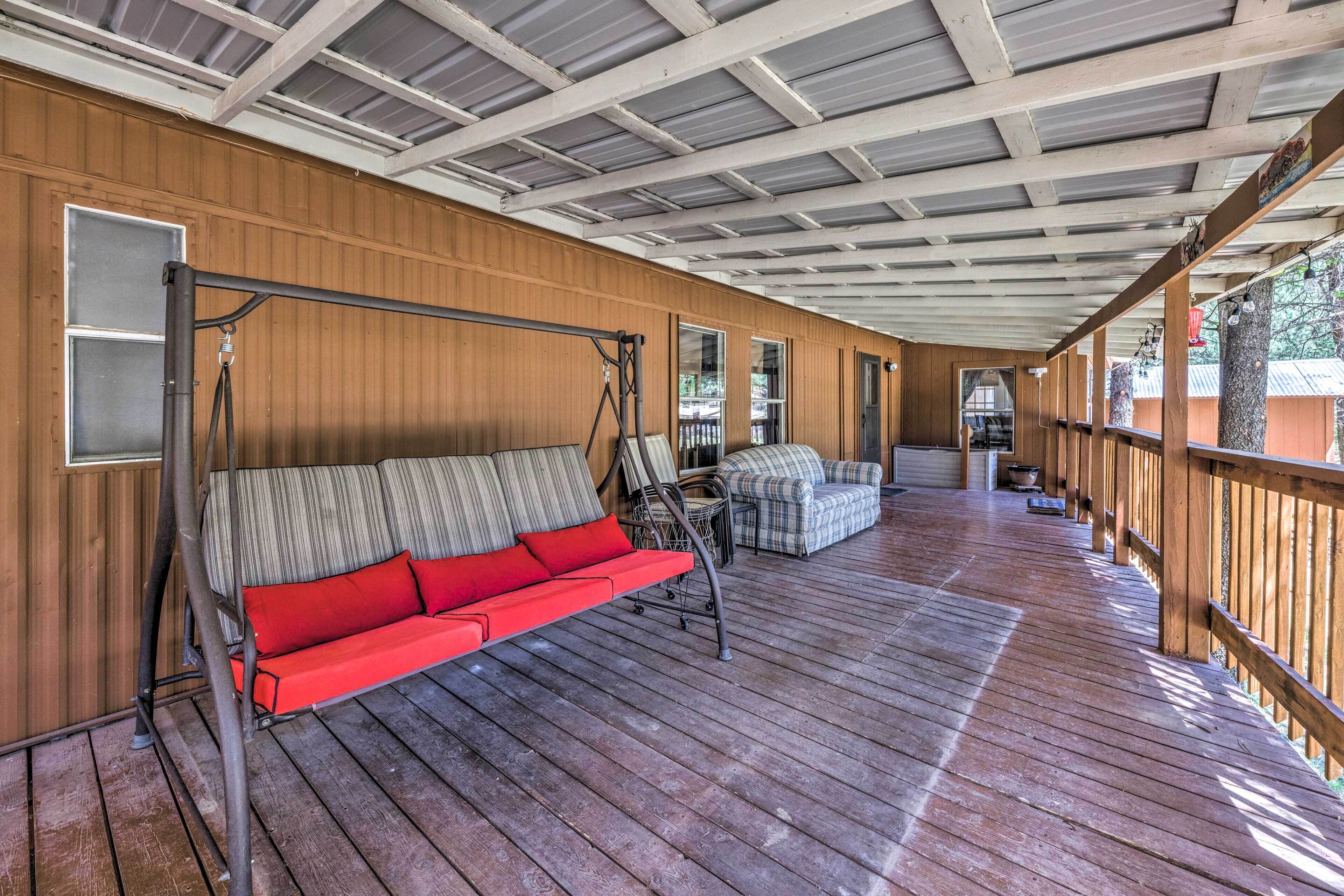 A covered porch with a swing seat, a cushioned bench, and a small table.