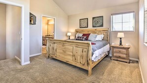 Un dormitorio con una cama de madera, dos mesitas de noche y un ventanal con persianas.