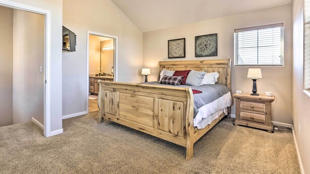 A bedroom with a wooden bed, two bedside tables, a nightstand, and a window with blinds. - Pet-friendly Fraser Condo, Sleeps 10, Near WP (Fraser)
