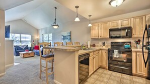 Una cocina amplia con armarios de madera, microondas integrado, lavavajillas y estufa. Cuenta con una zona de comedor con mesa y sillas.