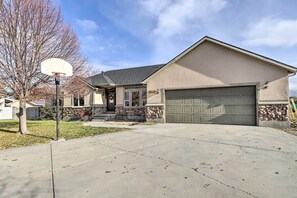 A residential house with a garage, a basketball hoop, and a stone wall. - Riverton Home w/ Gas Grill & Private Deck! (Riverton)