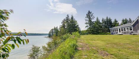 A lakeside property with a house, grassy areas, and trees.