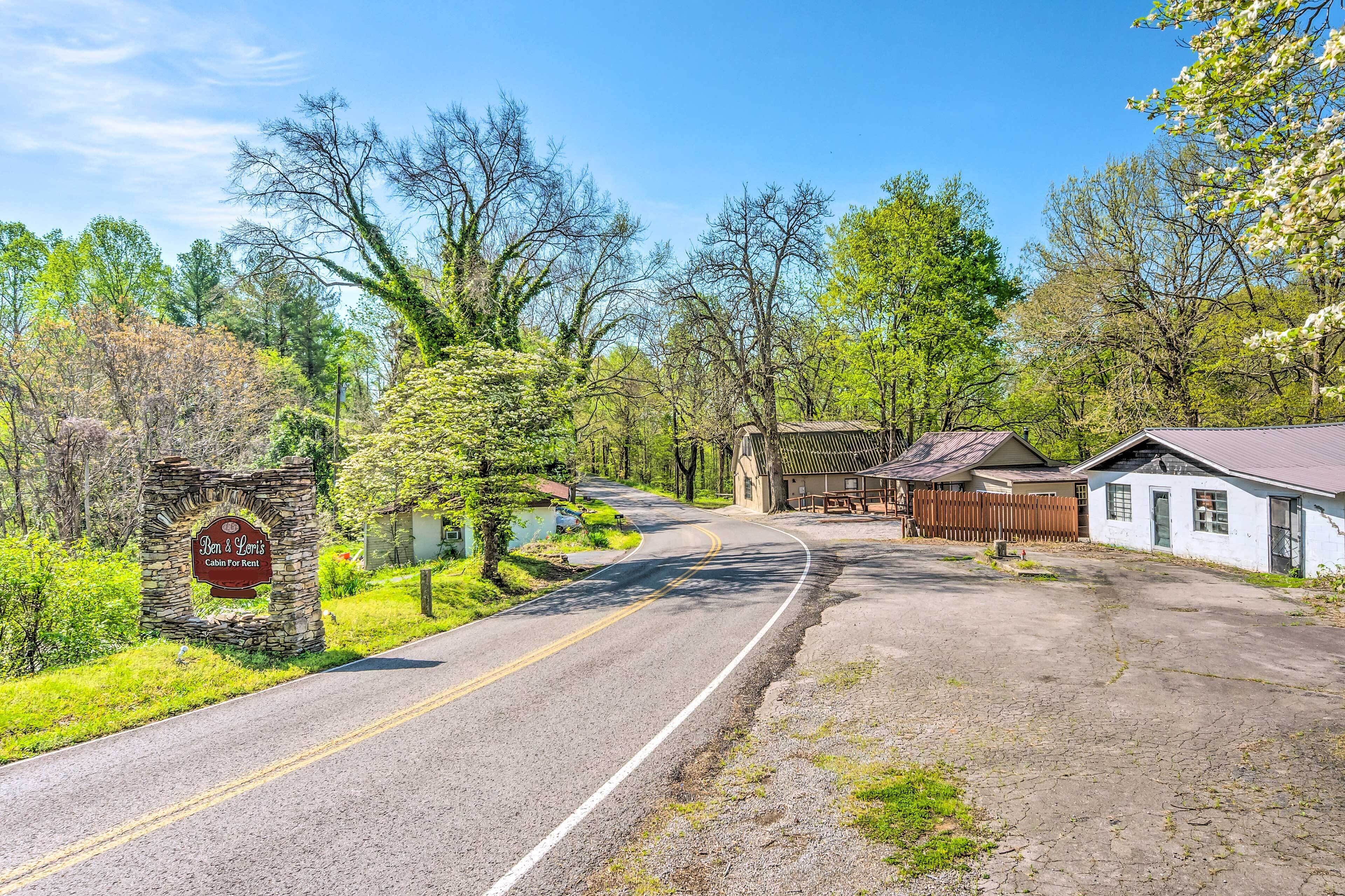 A cabin for rent named Ben & Lewis, surrounded by trees and a gravel driveway.