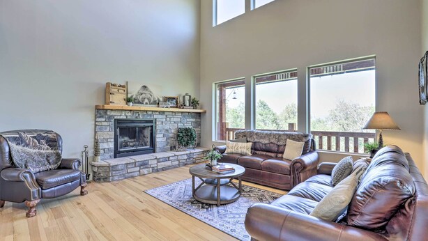 A spacious living room with a stone fireplace, leather sofas, and a large window providing natural light. - Spacious Resort Cabin in Manti-la Sal Mtns! (Fairview)