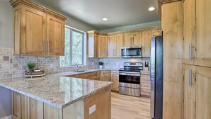 A modern kitchen with wooden cabinets, granite countertops, stainless steel appliances, and a large window providing natural light. - Spacious Resort Cabin in Manti-la Sal Mtns! (Fairview)