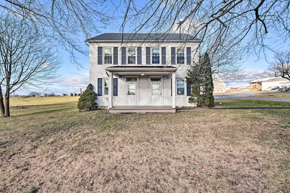 A two-story house with a front porch, a small front yard, and a clear sky.