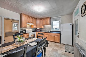A kitchen with wooden cabinets, a dining table set for four, a microwave, and a refrigerator.