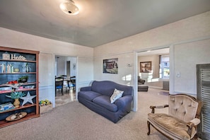A spacious living room with a grey sofa, a wooden bookshelf, and a classic armchair.