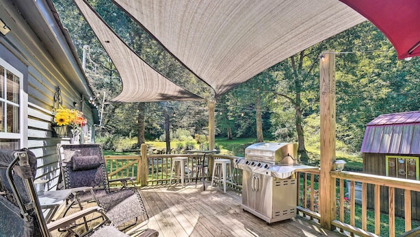 A covered deck with outdoor furniture, a grill, and a wooden structure in the background. - 'the Creek' Winfield Gem: 73 Acres of Privacy (Winfield)
