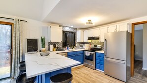 A modern kitchen with a large island, blue cabinets, stainless steel appliances, and a chalkboard with "WiFi" written on it. - Poconos Chalet With Lake & Pool Access! (Tobyhanna)