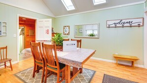 Un comedor con mesa y sillas de madera, un cartel que dice 'welcome', un espejo y un banco.