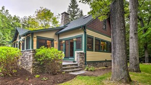 A two-story house with a stone foundation, green trim, and a chimney.