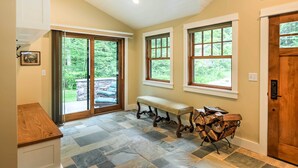 A hallway with a stone floor, wooden bench, and a door with a window.