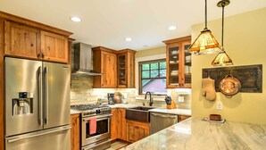 A modern kitchen with stainless steel appliances, wooden cabinets, and a marble countertop.