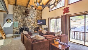 Una sala acogedora con chimenea de piedra, un sofá modular grande y un televisor.