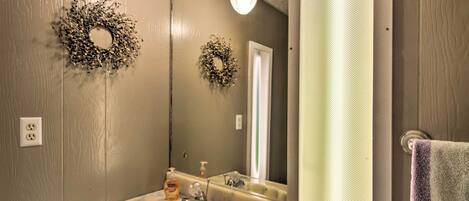 A bathroom with a sink, mirror, and two wall-mounted light fixtures.