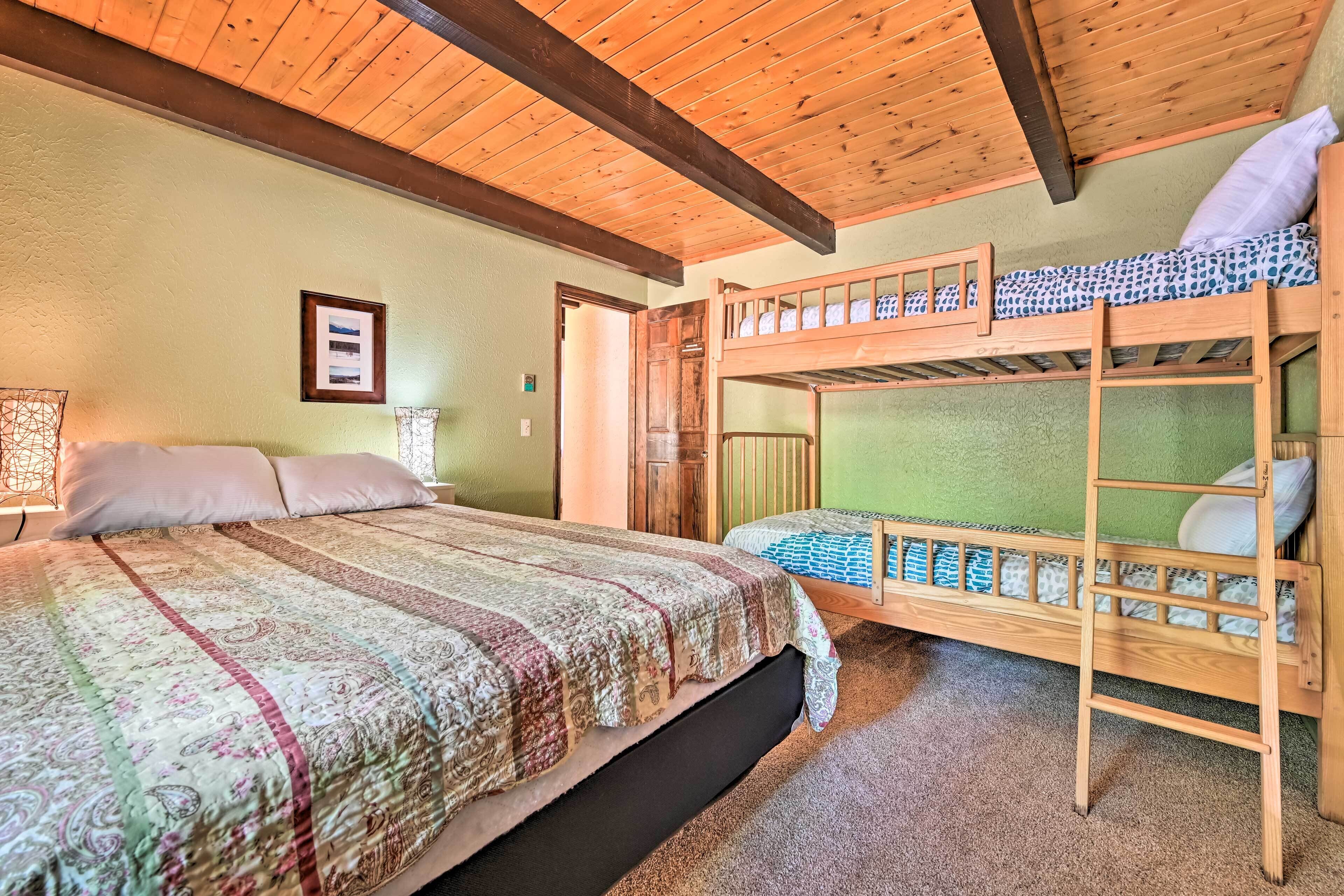Een kamer met een groot bed, een stapelbed en een houten plafond.