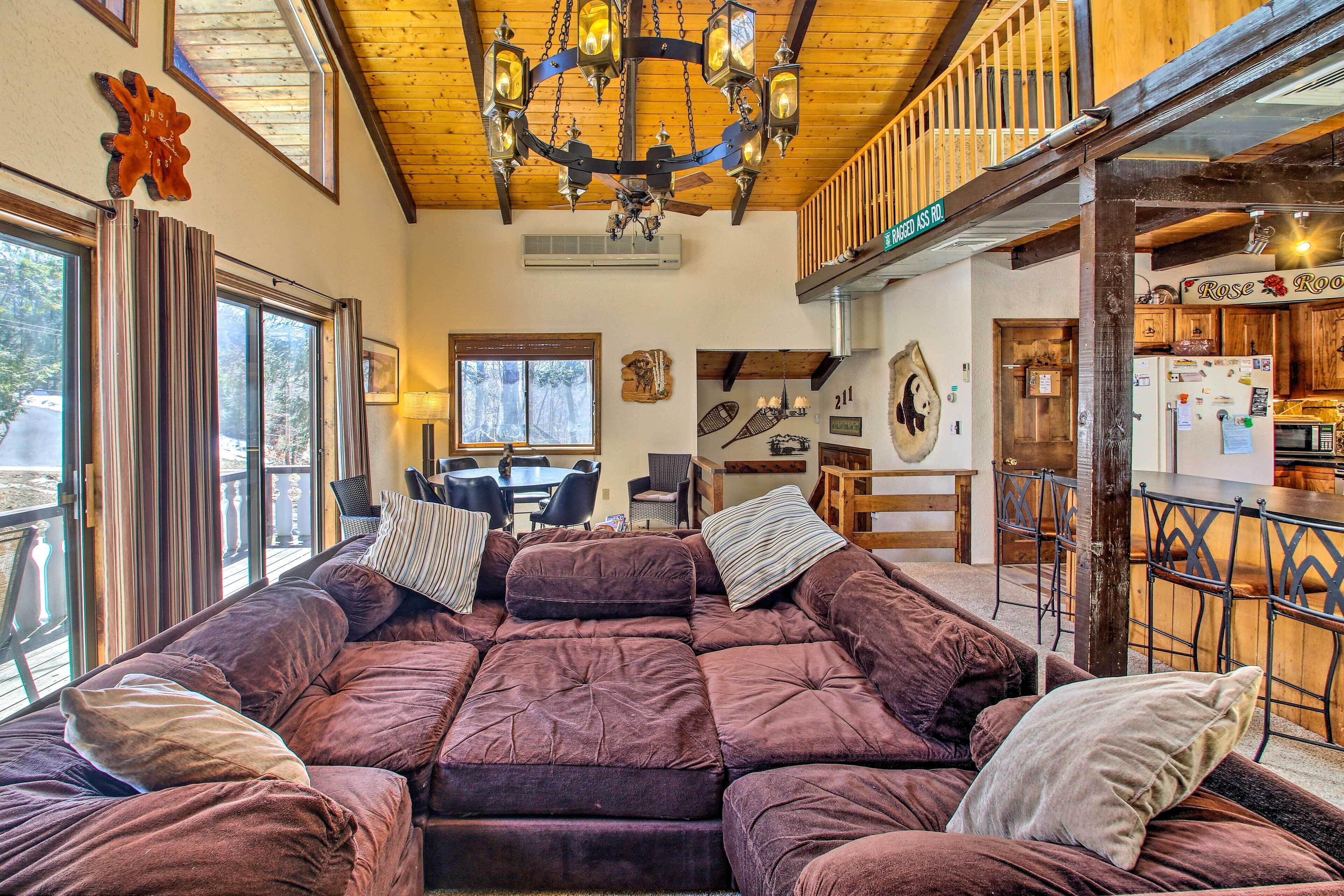 A cozy living room with a large sectional sofa, a chandelier, and a view of the outside.