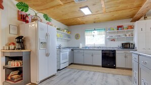 Une cuisine avec des meubles blancs, un réfrigérateur, un lave-vaisselle et un four à micro-ondes.