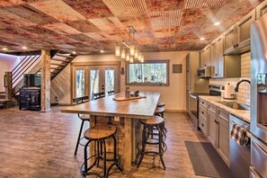 Una cocina amplia con una isla grande, taburetes de bar, electrodomésticos de acero inoxidable y un techo rústico.