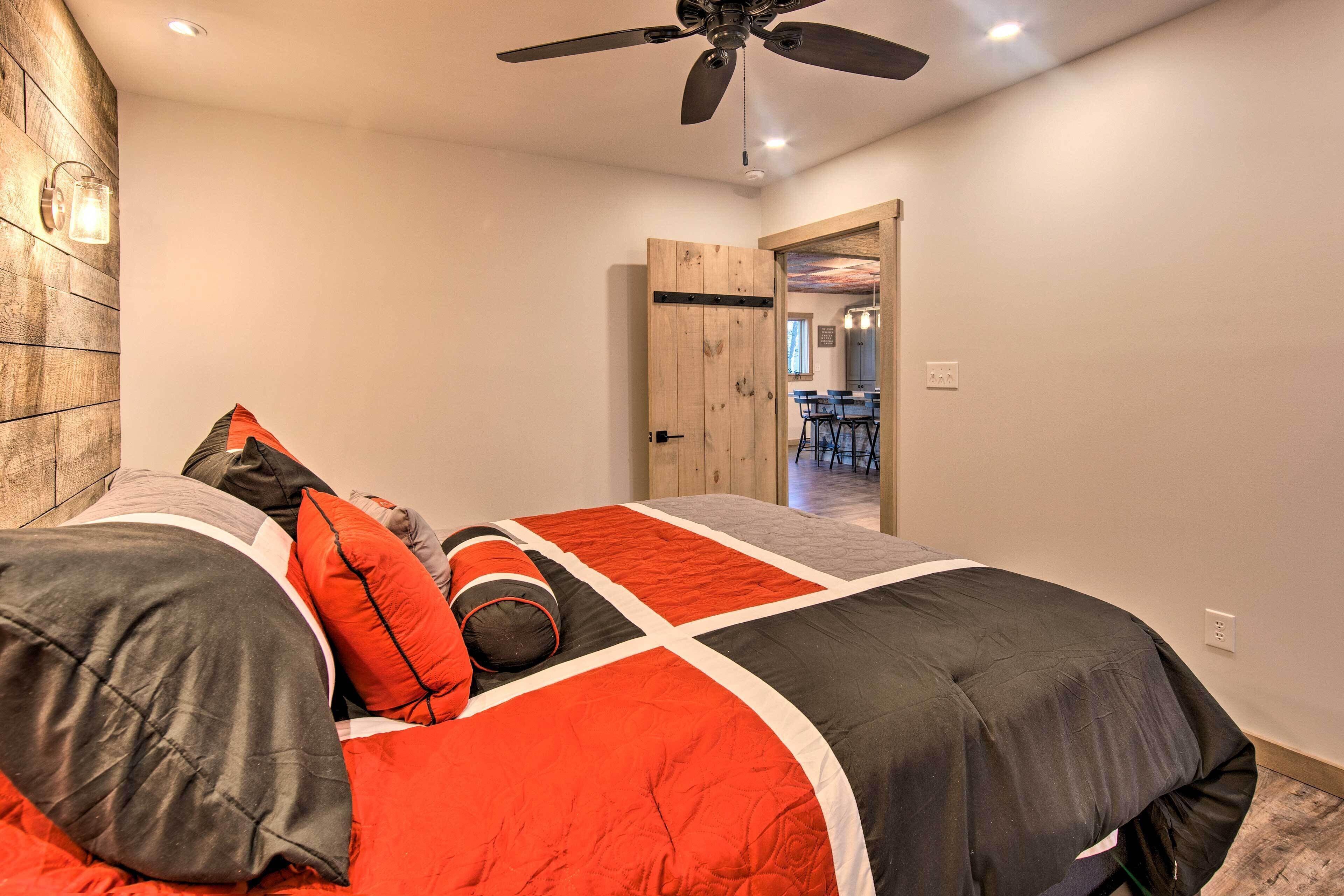 Un dormitorio con cama, ventilador de techo y puerta de madera que da a un comedor.