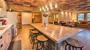 A spacious kitchen with a large island, bar stools, and a rustic ceiling. - 'timberland Estates' Cabin: Close to Trails! (Reedsville)