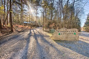 A gravel path leading to a cabin with a sign reading "Timberland Estates".