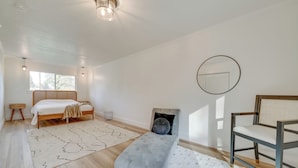 Un dormitorio con cama, mesita de noche, silla y un espejo redondo en la pared.