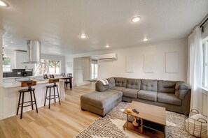 A modern living space with a kitchen, bar stools, a sectional sofa, and a coffee table. - Vancouver Vacation Rental 16 Mi to Portland! (Vancouver)